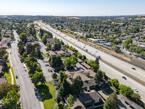 Aerial view of residential apartment complexes adjacent to Highway 4 with surrounding neighborhoods and the rolling hills of Antioch in the distance.
