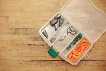 Fishing lead box in plastic box on wooden floor with copy space