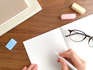 デスクでノートに字を書く女性の手元