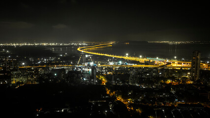 India's longest sea bridge: Trans-Harbour Sea Link. Atal Setu sea bridge in Mumbai, Maharashtra, India. Time-lapse of a city at night with bright skyscrapers and a dense network of glowing buildings.