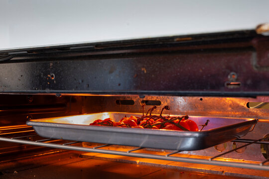 A view of a orange cherry tomatoes roasting under a broiler.