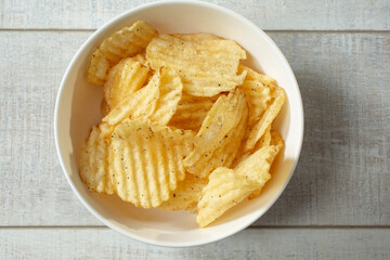 A top down view of a bowl of pepper flavored ridged potato chips.