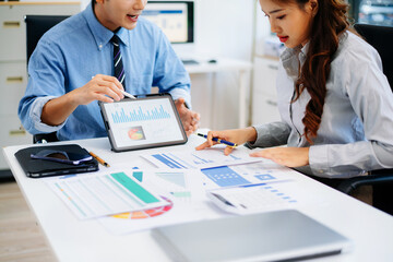 Fototapeta premium Two professionals reviewing business charts and data with tablet and documents. Ideal for financial planning, corporate teamwork, and modern office