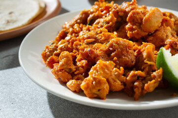 A closeup view of a pile of pollo asado meat on a plate.