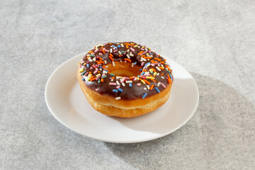 A view of a chocolate rainbow sprinkle donut.