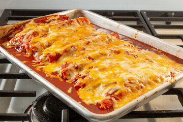 A view of a baking sheet of enchiladas.
