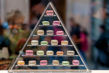 Pyramid of macaroons in a variety of colors seen through the window glass