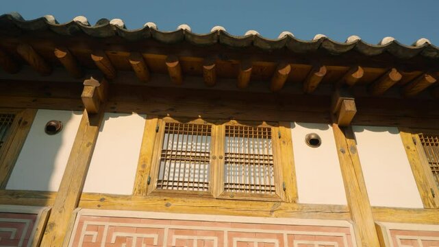Sunlight glints off wooden lattice windows and tiled eaves of a hanok in Bukchon Hanok Village, Jongno-gu, Seoul
