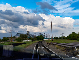 A view of a train track with a factory in the background