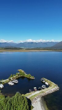 Aerial vertical drone fly in New Zealand's Lake Brunner underneath Southeren Alps, natural landscape, campsite view