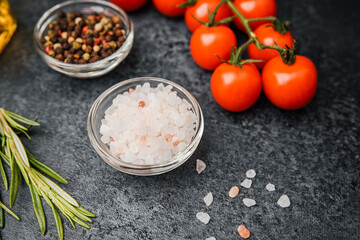 Pink himalayan salt with cherry tomatoes pepper and rosemary on dark background