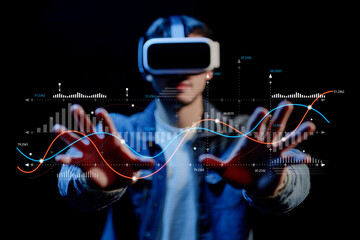 Young man wearing virtual reality headset interacting with digital data visualizations against a...