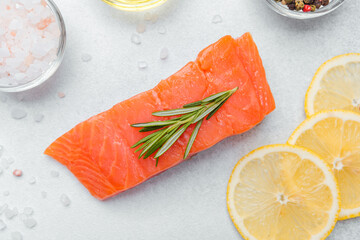 Fresh salmon fillet garnished with lemon slices and herbs in a kitchen setting