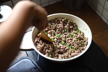 female hands stir fry ground beef and basil