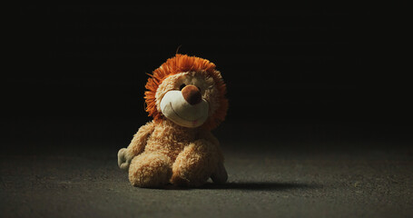 Dark, shadow and teddy bear in studio for loss, isolation and forgotten toy on ground. Night, floor...
