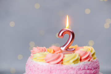 Celebration of a second birthday with a colorful cake and glowing candle