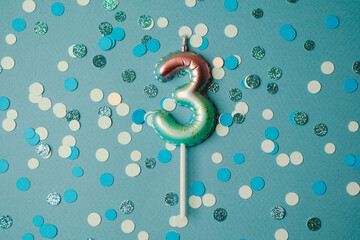 Colorful three-shaped candle with confetti for birthday celebration