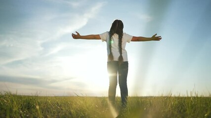Child praying outdoors with open arms. Peaceful child praying in nature. Back view child in prayer. Kid spiritual moment outdoors. Child asking for blessings in open field. Praying embracing nature.