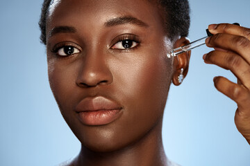 Skincare routine with serum application by a woman in a studio setting