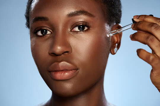 Skincare routine with serum application by a woman in a studio setting