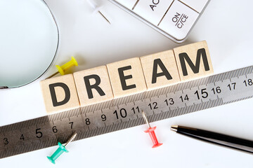 Dreams word written on wooden cubes, arranged according to a ruler using a magnifying glass and...