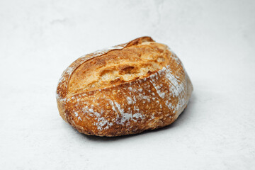 Freshly baked loaf of artisanal bread resting on a white surface