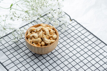 Cashews placed in a wooden bowl on a wire rack with floral accents