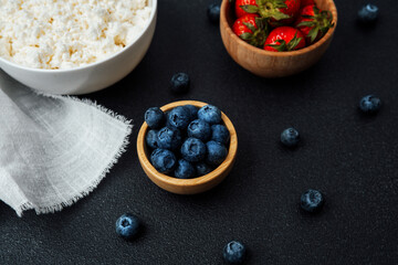 Fresh blueberries and strawberries served with cottage cheese on a dark table