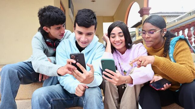 Latino high school students using smartphones sitting on school steps, video 4k real time