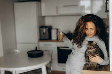 Woman Enjoying Coffee in Kitchen While Bonding with Her Pet Cat