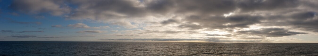 A cloudy sky with a calm ocean in the background