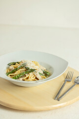 Creamy spaghetti with chicken and asparagus resting on wooden table