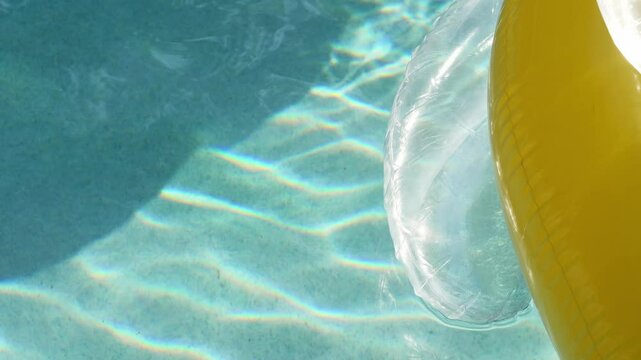 Ripples of light in a sunny pool with a yellow float in slow motion