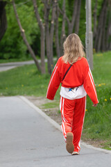 A woman walks along a park alley on a spring day