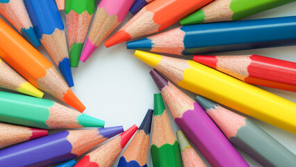 Close-up of colorful sharpened pencils arranged in a circular pattern on white background