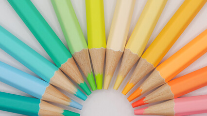 a semicircular fan of colored pencils, focusing on cool greens, aquas, and blues on the left, transitioning into yellows and warm oranges on the right