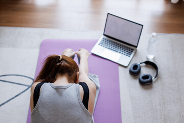 young asian woman exercising doing workout at home in front of laptop
