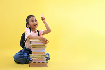 Little Asian Girl Sitting Wearing Casual Clothes and Jeans, Pointing to the Top, Her Hand on...