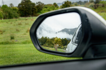 View of mountains in the car side mirror. West Coast. South Island.