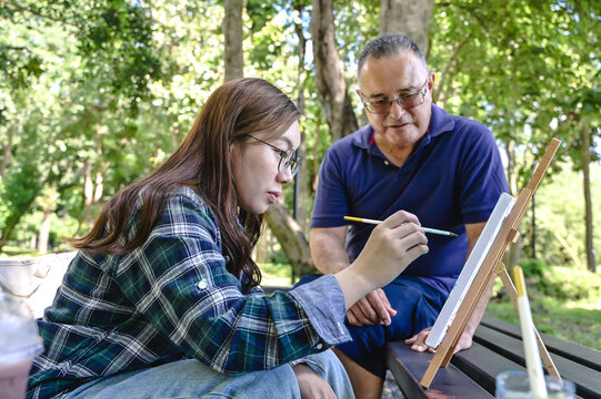 Young female collage students studying art class with senior art teacher outdoor campus