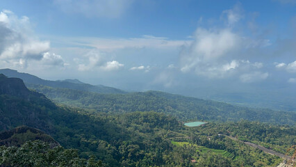 Fototapeta premium Breathtaking Panoramic View of Lush Green Mountains and Serene Lake Under a Cloudy Sky