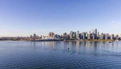 Fototapeta premium Breathtaking View of Downtown Vancouver Skyline Reflecting on Calm Water Under Blue Sky