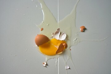 A broken egg on a kitchen floor after a fall, conceptual image, never give up, never lose hope, the shape of the egg looks like a chicken trying to fly.