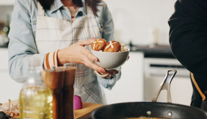 People, hands and cooking with bowl of mushrooms for vegetarian snack, ingredients or meal prep at home. Chef, assistant and vegan recipe with organic vegetables or food for hospitality at house