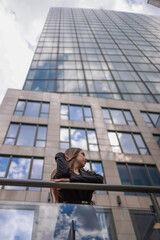 Fototapeta premium Portrait of a beautiful woman against the background of a modern high-rise building.