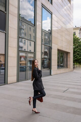 Naklejka premium Beautiful girl in patent burgundy shoes against the background of a business center.