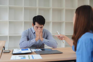 Obraz premium Stressed businessman covering face while businesswoman arguing at office desk