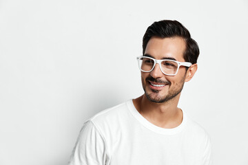 Naklejka premium Smiling man wearing white glasses and t-shirt poses against a plain white background, showcasing a cheerful expression, capturing a moment of confidence and style.
