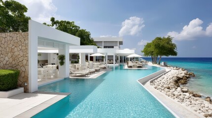 Fototapeta premium Hotel infinity pool overlooking ocean, turquoise water, clear sky, luxurious vibe.
