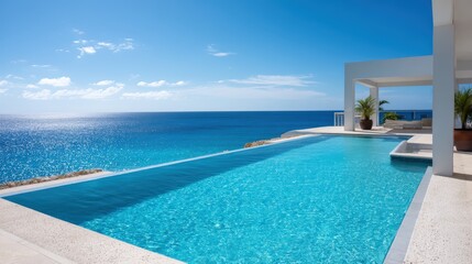 Fototapeta premium Hotel infinity pool overlooking ocean, turquoise water, clear sky, luxurious vibe.